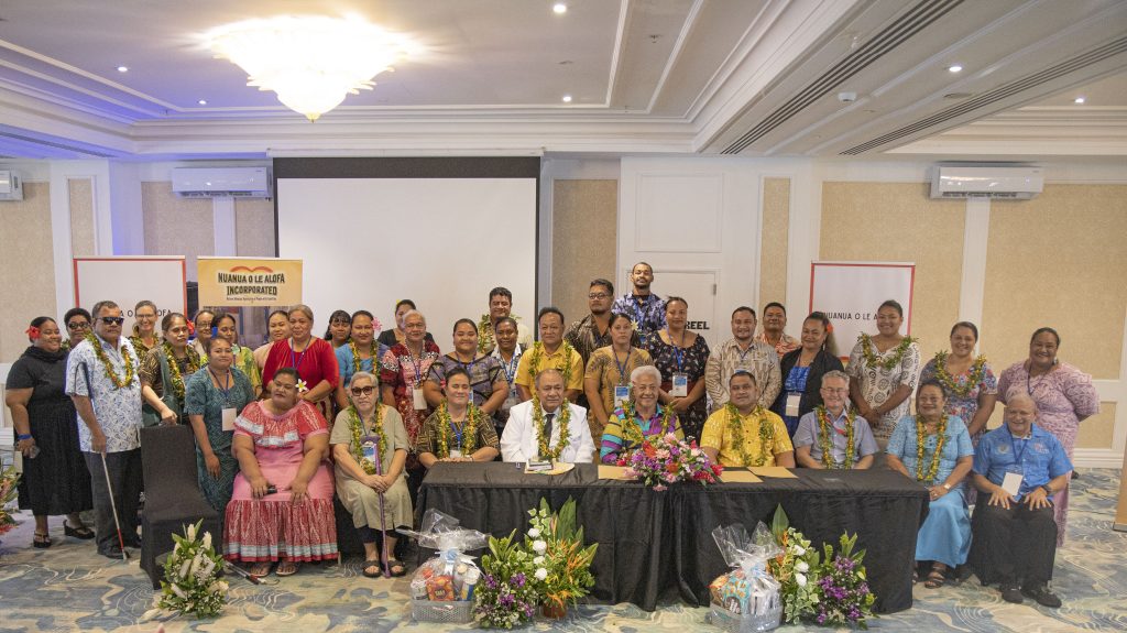 A group of Polynesian activists are seated and standing inside a conference room.