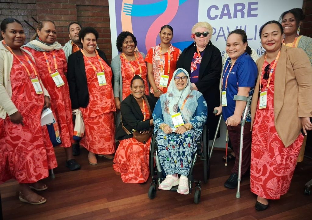A group of Pacific disability activists wearing matching floral outfits with DRF staff member Dwi Ariyani